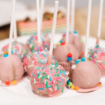 party-handmade-pink-cake-pops-with-colorful-sprinkles-white-sticks-white-ceramic-plate-sweet-candy-bar